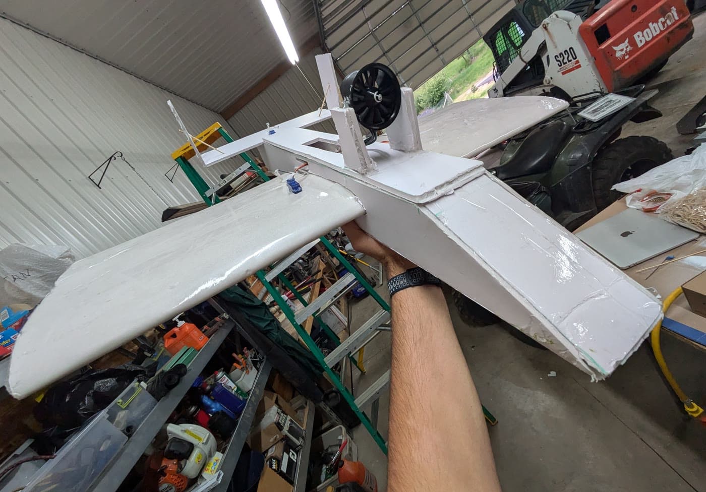 A hand-built foam airplane held up in a workshop