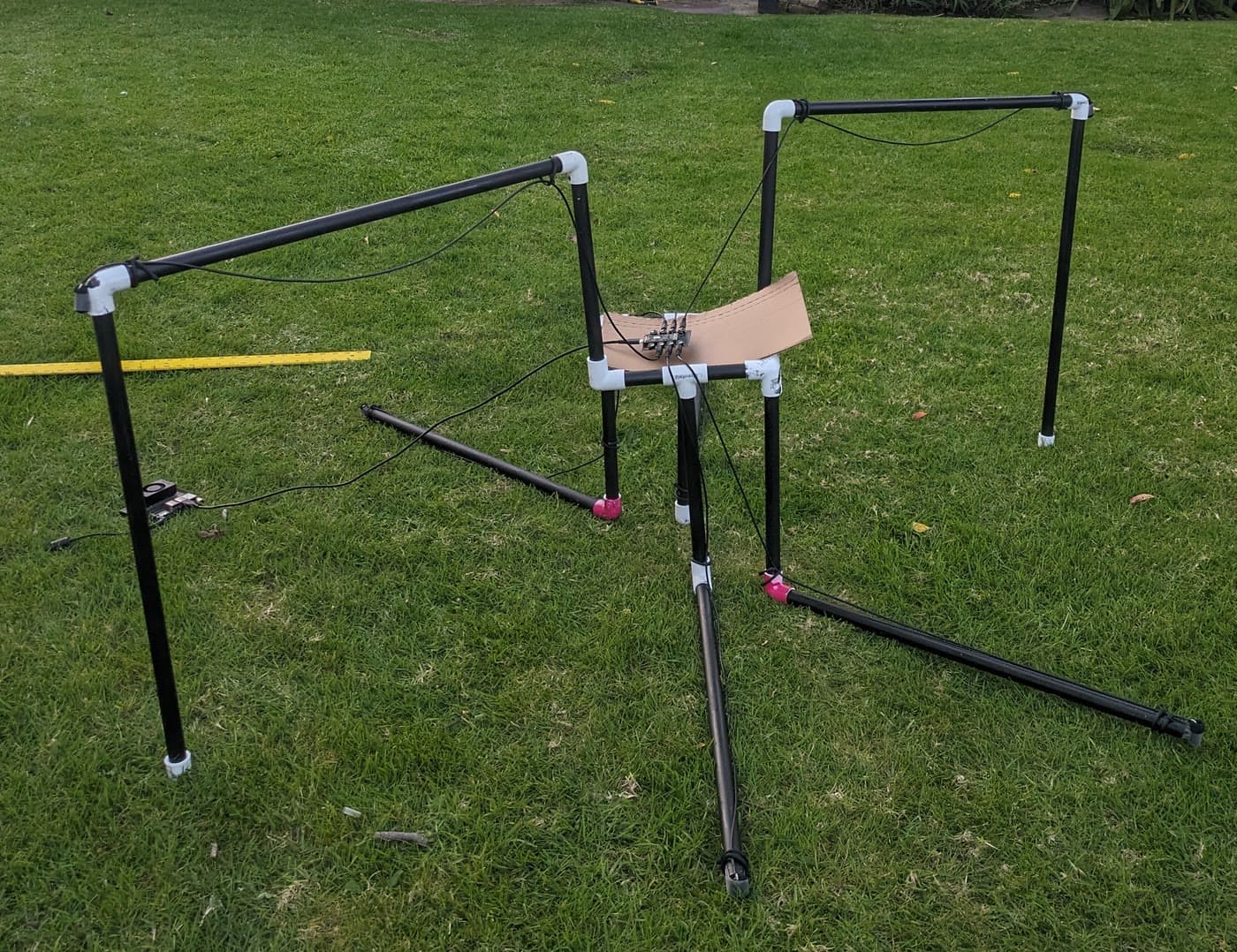 A PVC pipe test rig with a circuit board at its center, set up on a lawn